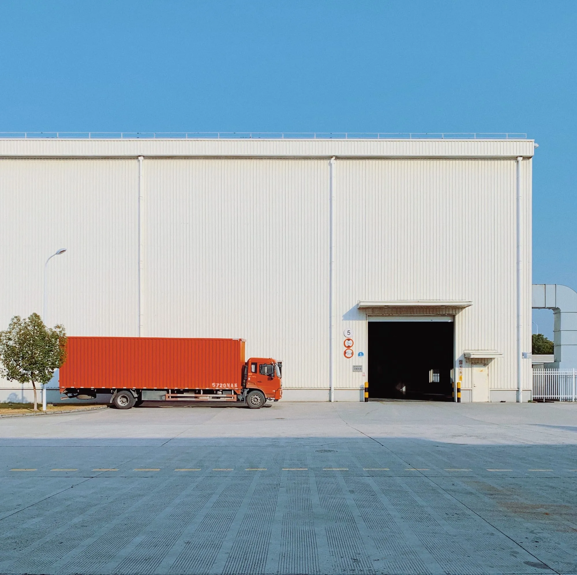 A box truck parked beside the loading door of a warehouse